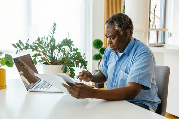 Blog man at table with laptop paperwork