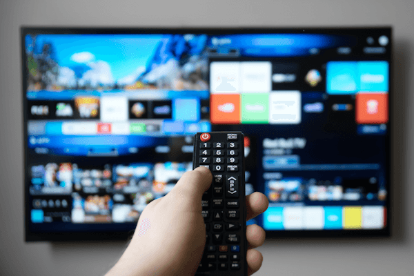 Blog hand holding remote with tv interface in background Blog hand holding remote with tv interface in background