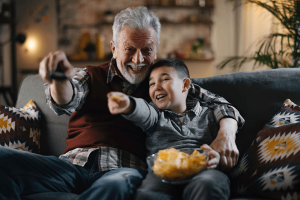 Blog man and child on couch with remote and snacks Blog man and child on couch with remote and snacks